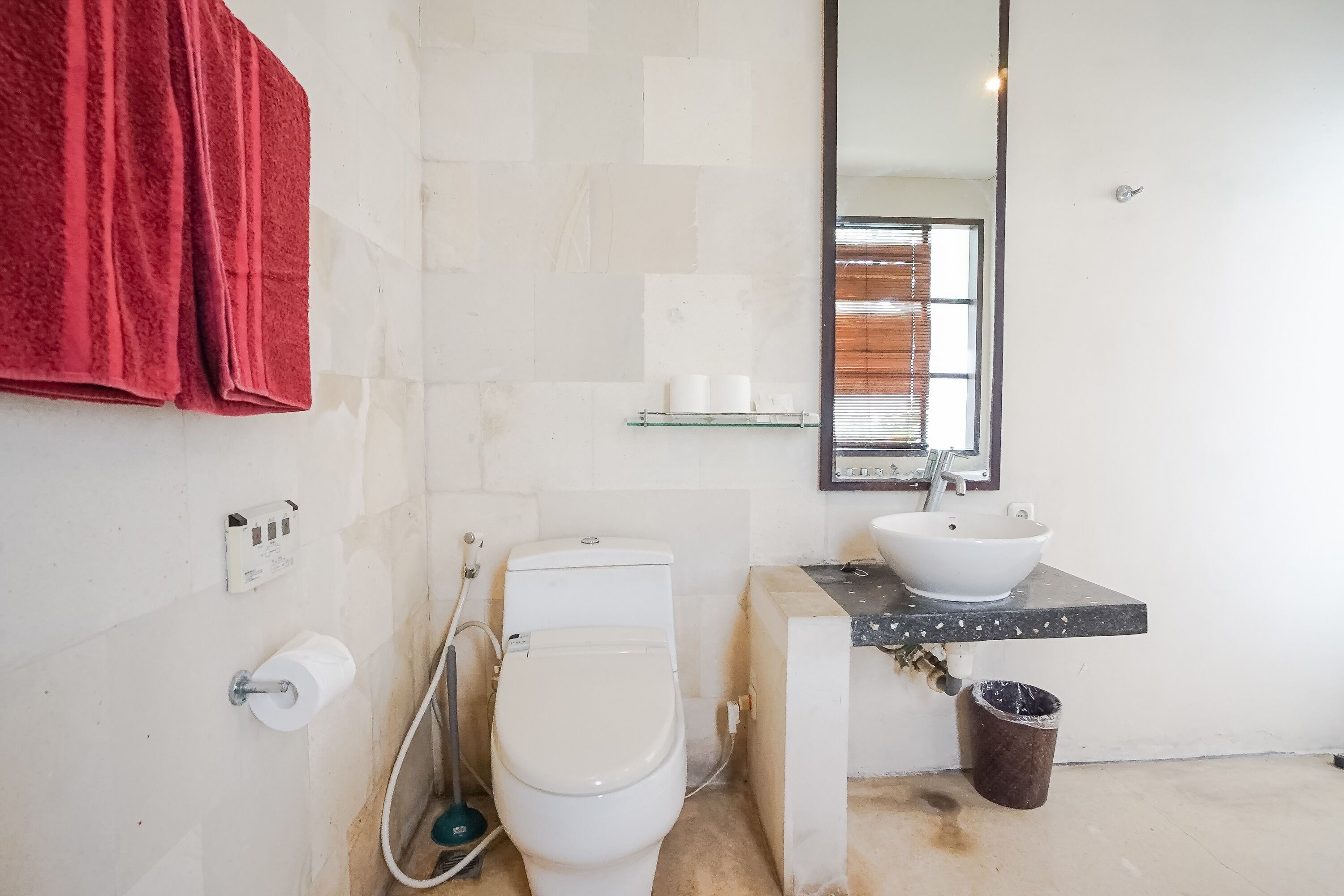A bathroom with a toilet, sink, and a mirror.