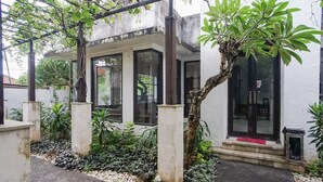 Um edifício moderno com varanda coberta, janelas amplas e uma pequena entrada com degraus.