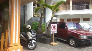 Un bâtiment avec une enseigne indiquant « GEDUNG WAHYUTMA » et un panneau interdisant le stationnement.