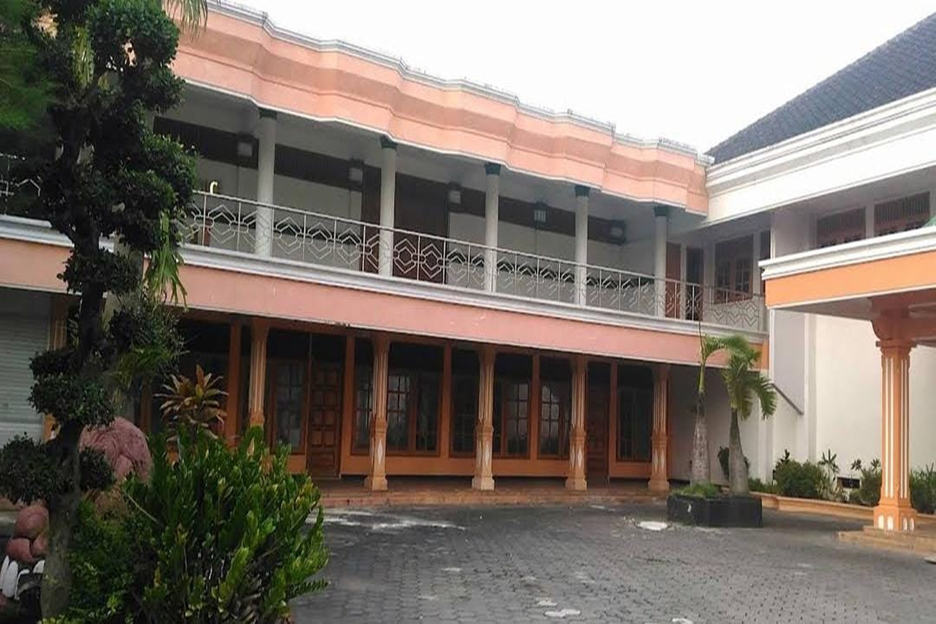 Ein Gebäude mit überdachtem Gang, Säulen und einem Balkon mit schmiedeeisernen Geländern.