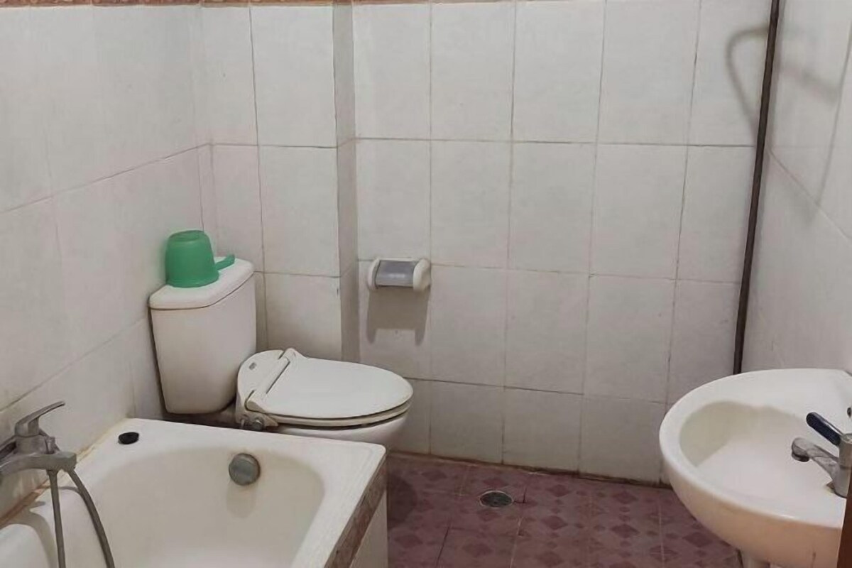 Une petite salle de bain avec des toilettes, un lavabo et un distributeur d’eau vert.
