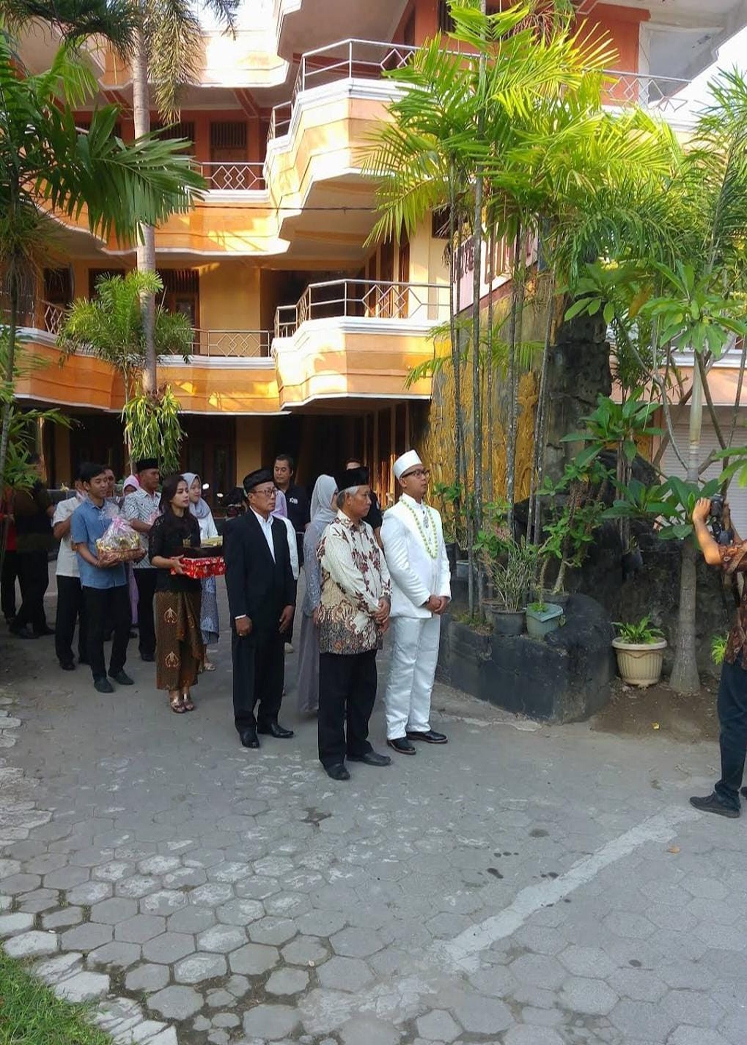 A group of people standing in a courtyard with a building in the background.