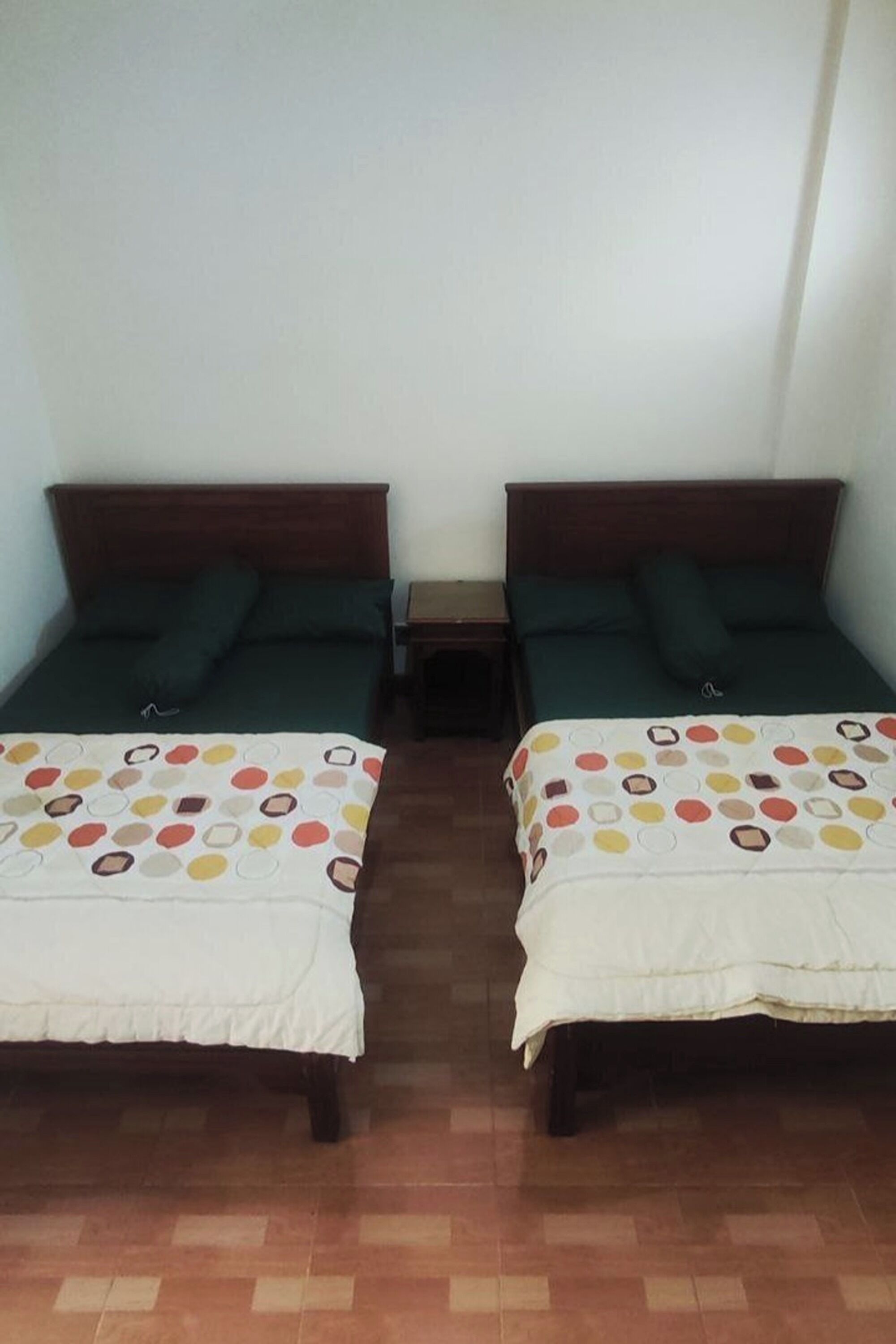Deux lits jumeaux avec des têtes de lit assorties, une petite table de chevet et un mur sobre.