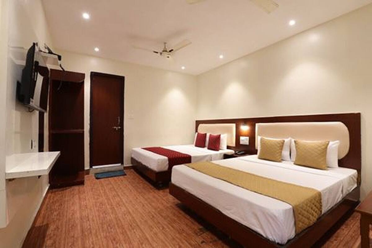 A hotel room with two beds, a wardrobe, a TV, and a ceiling fan.