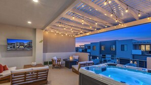 Eine Dachterrasse mit Whirlpool, Sitzgelegenheit und Lichterketten.