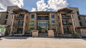 A multi-story building with a central entrance, stone pillars, and a large glass facade.