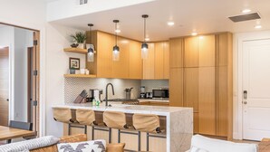 A modern kitchen with wooden cabinets, a central island, and pendant lighting.