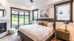 A bedroom with a large bed, a fireplace, and a view of the outdoors.