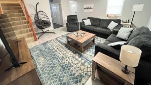 A living room with a staircase, a sofa set, a coffee table, and a lamp.