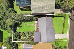 An aerial view of a residential area with a house featuring a sloped roof, a stone wall, and a well-maintained lawn. - "Family Tides" – Short Stroll to the Beach (Copacabana)