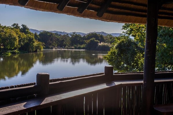 A wooden deck overlooking a calm lake with surrounding greenery and hills.