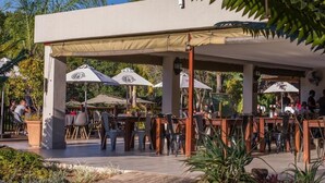 An outdoor cafe with tables and chairs under a canopy, surrounded by greenery. - Kruger Park Lodge Unit No. 209 (Mbombela)