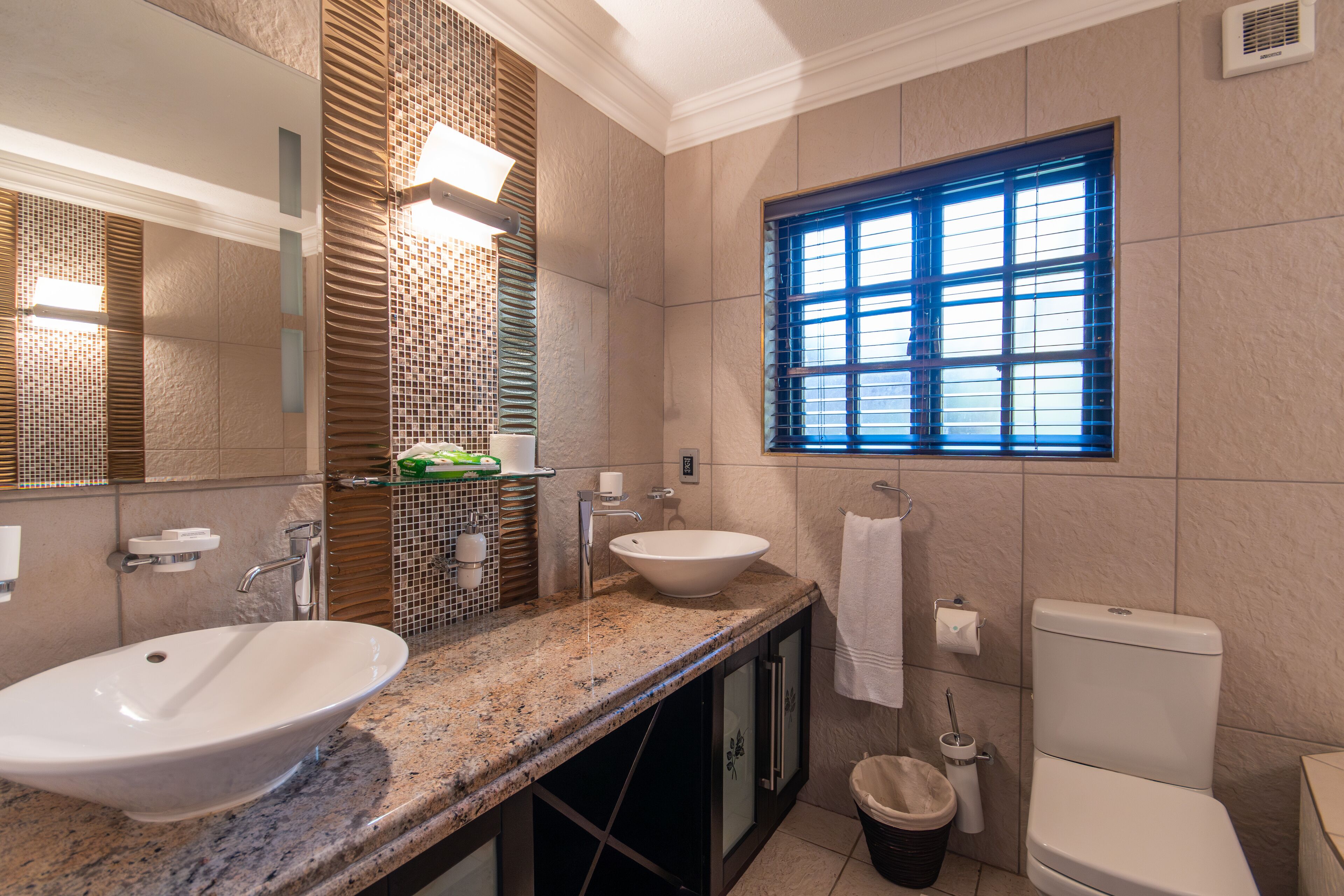 A bathroom with two sinks, a window, and a toilet.