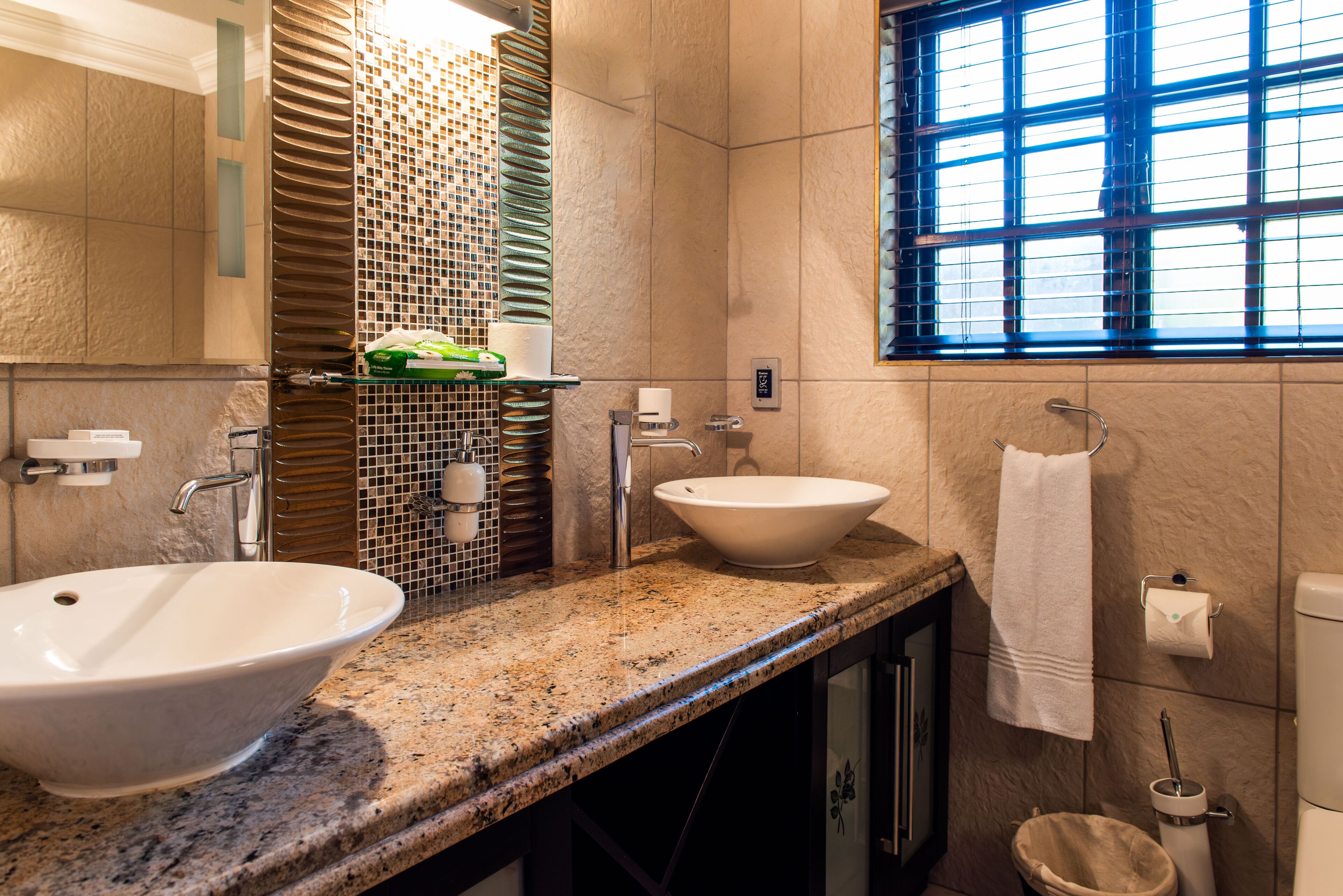 A bathroom with two sinks, a window, and a towel rack.