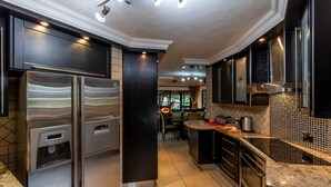 A modern kitchen with stainless steel appliances, a water dispenser, and a dining area with a view. - Kruger Park Lodge Unit No. 209 (Mbombela)