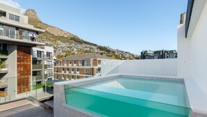 A rooftop pool with a clear view of a mountain and residential buildings in the background. - The Avant 303 (Cape Town)