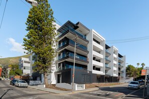 A multi-story modern building with balconies, a street view, and a clear sky. - The Avant 303 (Cape Town)