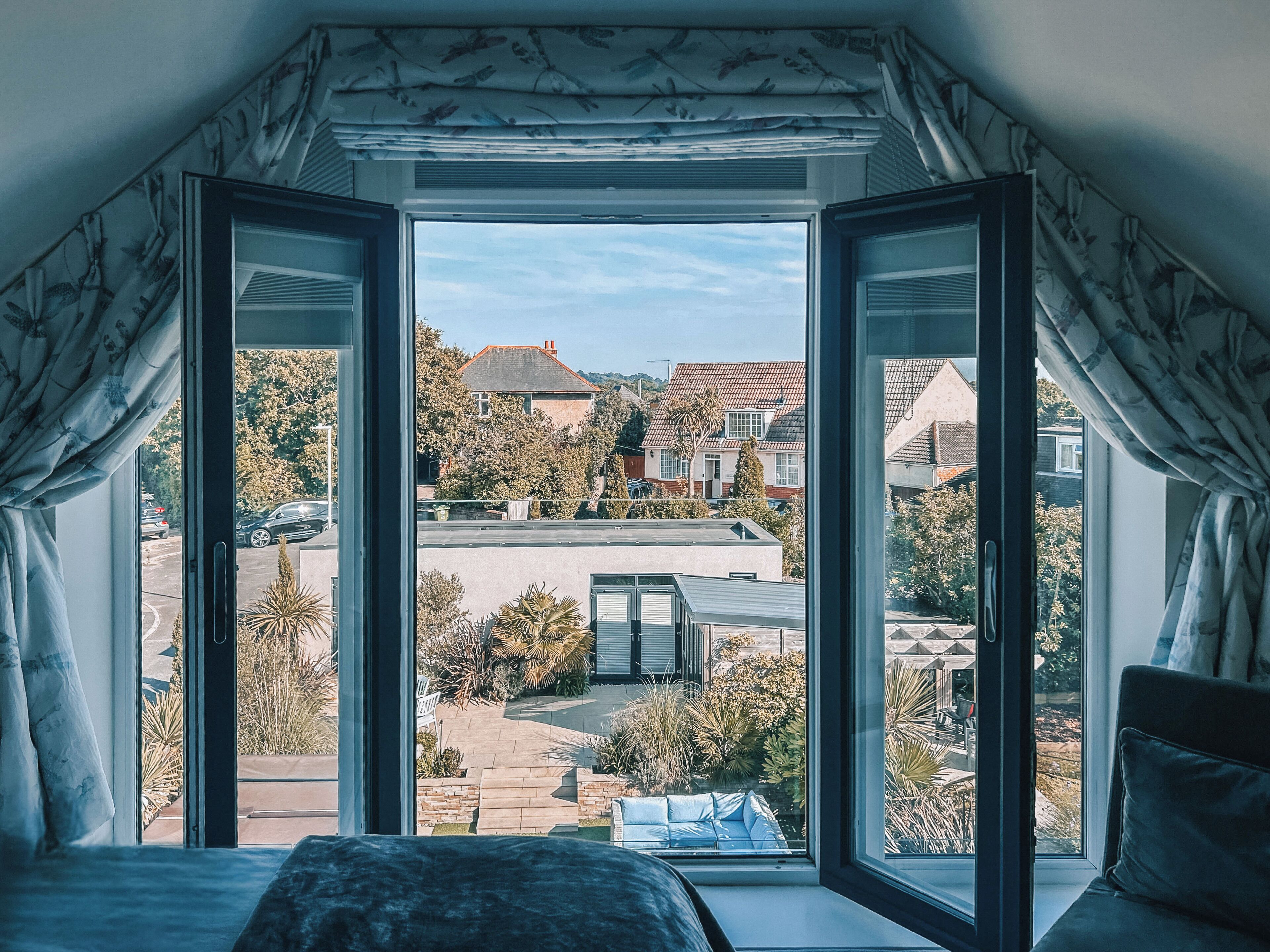 Una camera da letto con un'ampia finestra, un letto e vista su una zona residenziale.