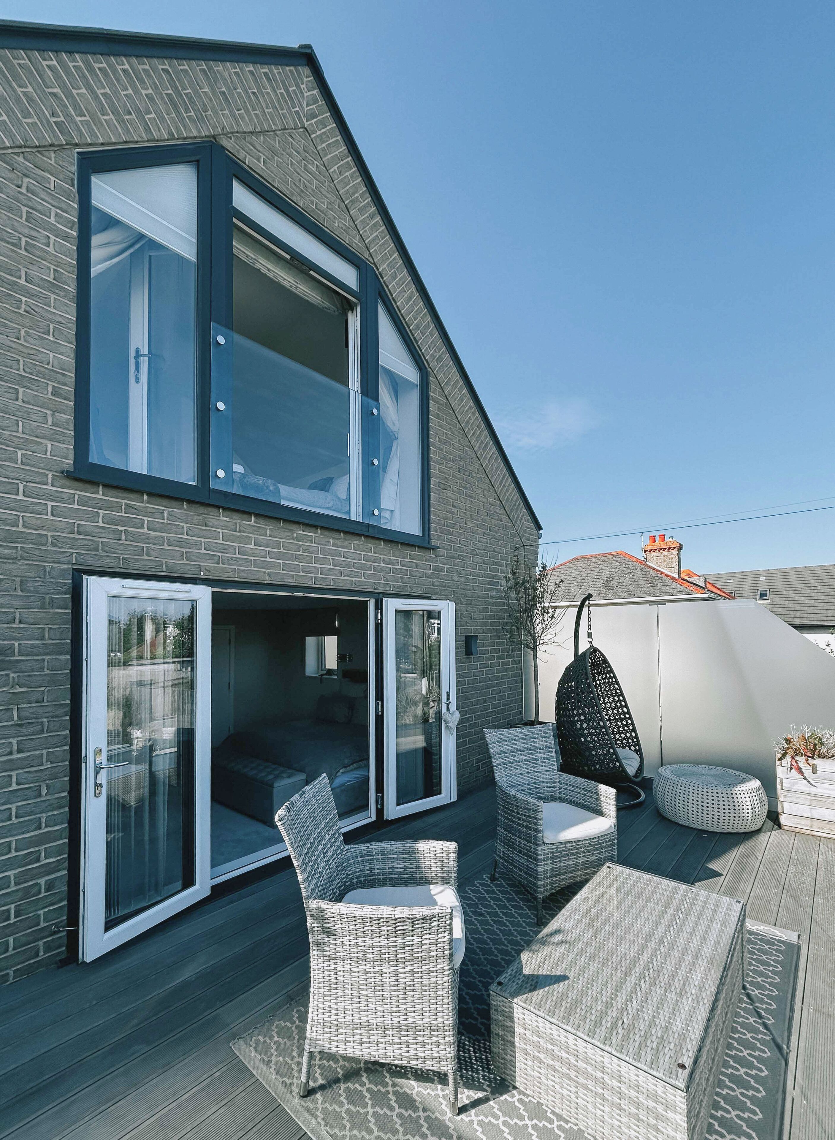 A modern house with a large glass door leading to an outdoor patio area.
