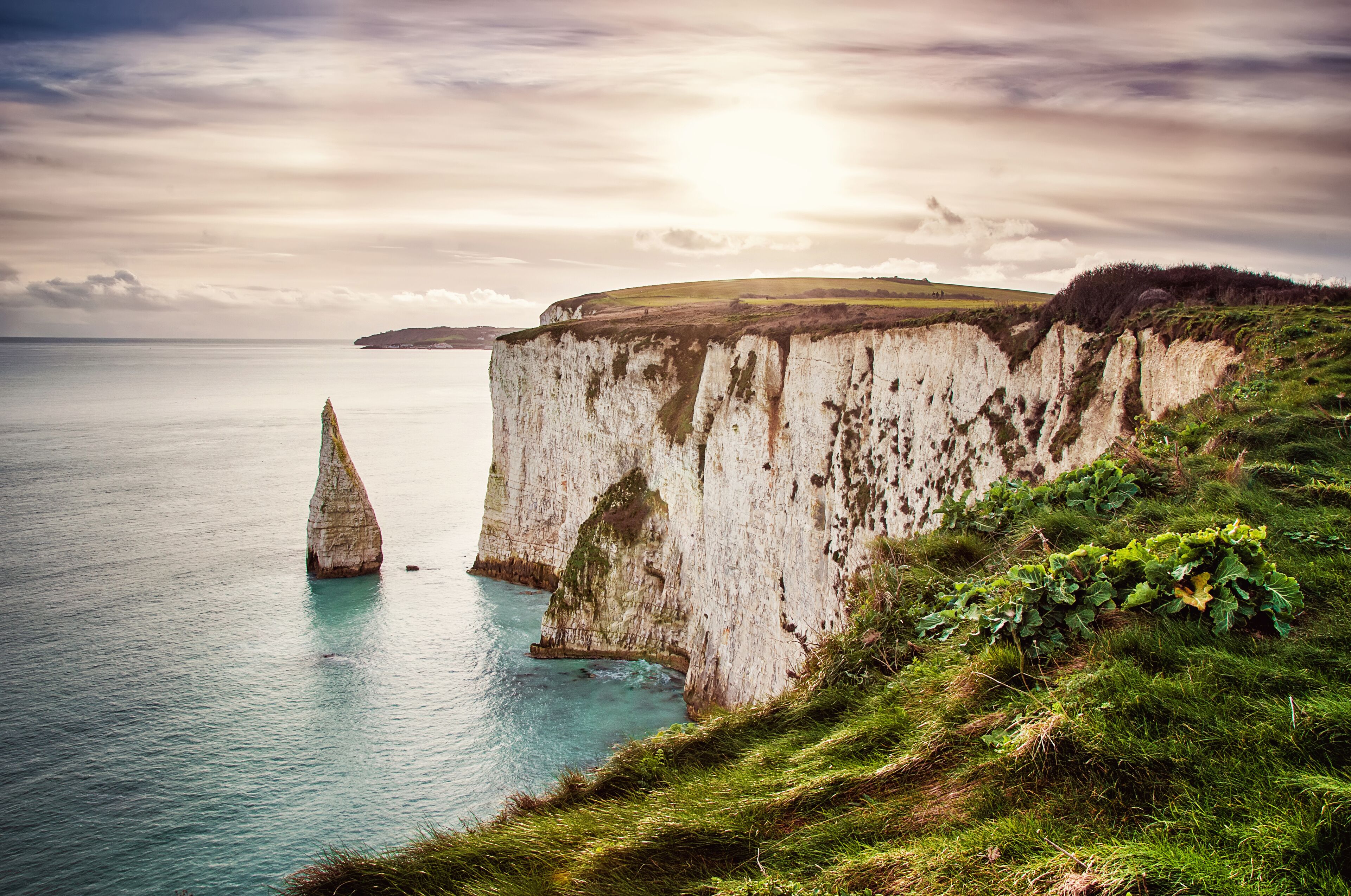 A coastal cliff with a prominent white rock formation and a small island.