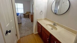 A bathroom with a sink, mirror, and wooden cabinets. - Two-story, two-bedroom, blocks from Downtown New Braunfels, Comal River, and Texas Tubes (New Braunfels)