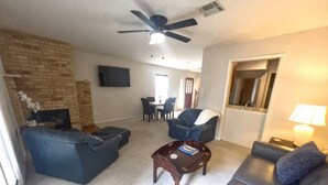 A living room with a fireplace, a ceiling fan, a dining area, and a sofa. - Two-story, two-bedroom, blocks from Downtown New Braunfels, Comal River, and Texas Tubes (New Braunfels)