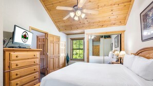 A bedroom with a wooden ceiling, a bed, a dresser, a desk with a computer, and a window with a view of greenery. - Fantastic Cabin Close to Branson Entertainment- Golf & Ticket Discounts! (Branson)