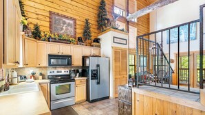 A kitchen with wooden cabinets, stainless steel appliances, and a wooden staircase. - Fantastic Cabin Close to Branson Entertainment- Golf & Ticket Discounts! (Branson)