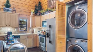 A compact kitchen with wooden cabinets, a refrigerator, an oven, and a washing machine. - Fantastic Cabin Close to Branson Entertainment- Golf & Ticket Discounts! (Branson)