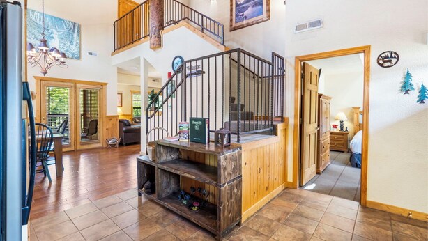 A spacious living area with a wooden staircase, a fireplace, and a dining area with a table and chairs. - Fantastic Cabin Close to Branson Entertainment- Golf & Ticket Discounts! (Branson)