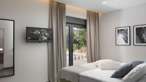 A modern bedroom with a bed, a TV, and a view of an outdoor area. - Stylish Villa with Pool (Labin)