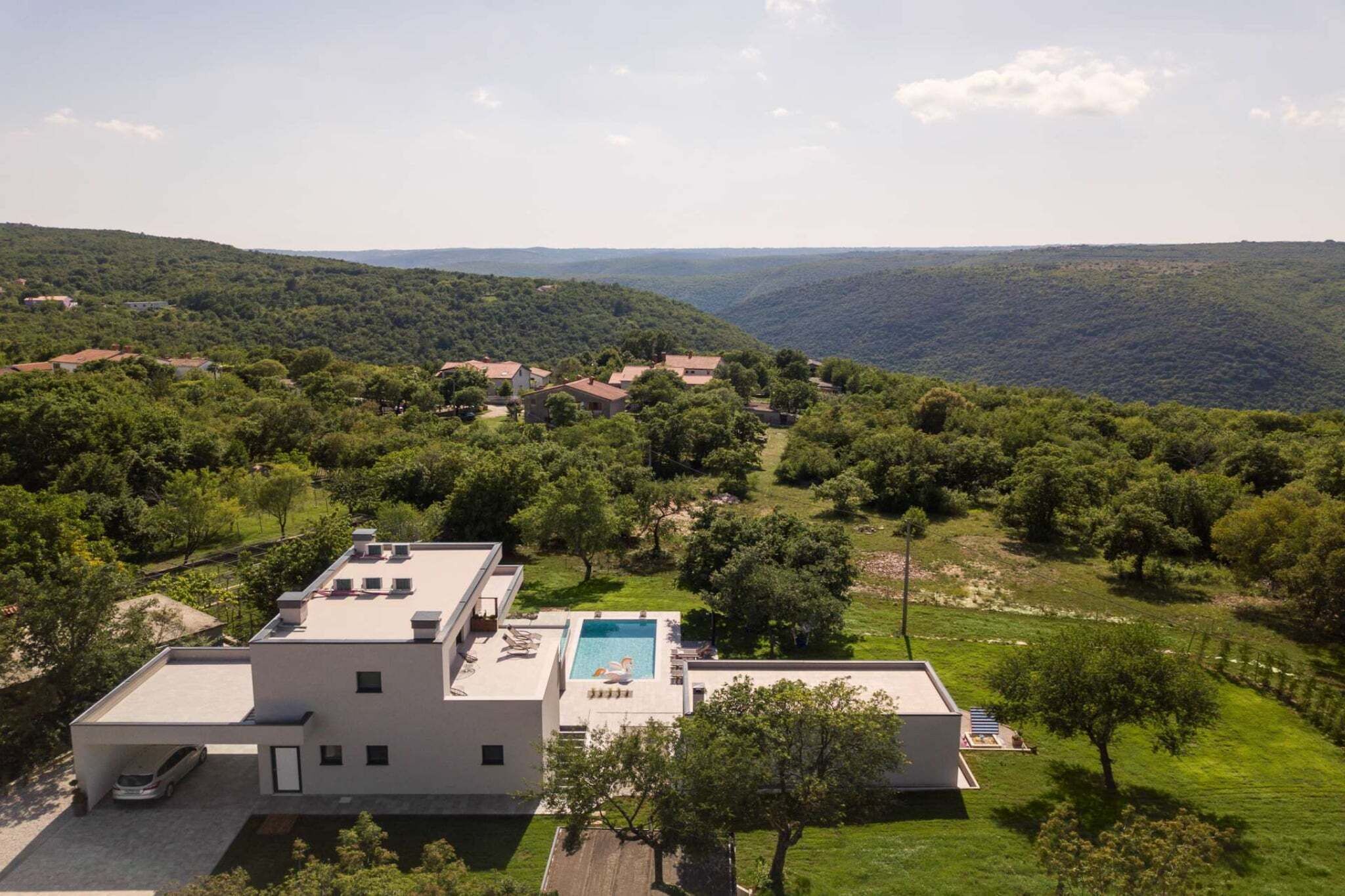 Una casa moderna con piscina, immersa nel verde e circondata da colline.