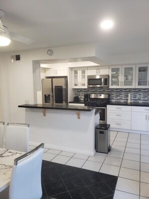 Fully equipped kitchen with a stainless steel refrigerator, microwave, and coffee maker.