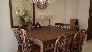 A wooden dining table with six chairs, two wall clocks, and a vase with flowers. - Pleasant holiday home in Vrbnik near Secret Beach (Vrbnik)