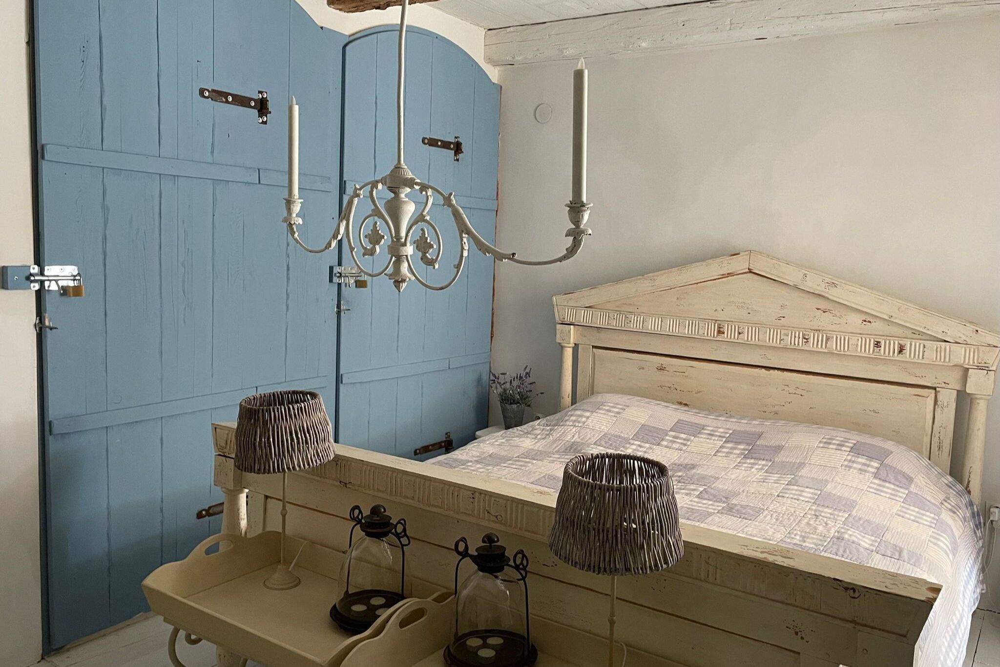 Een slaapkamer met een bed, een kroonluchter en een blauwe deur.