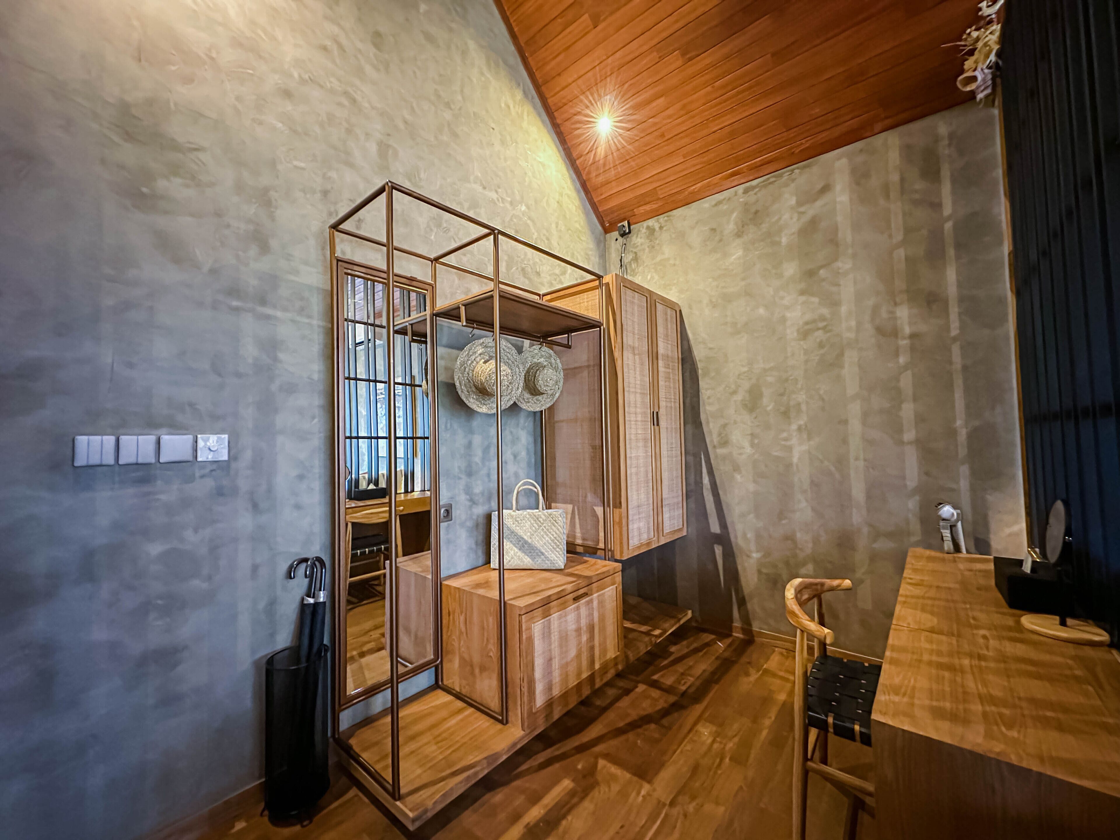 Une pièce avec un plafond en bois, une armoire intégrée dotée d’un miroir et une petite table avec une chaise.