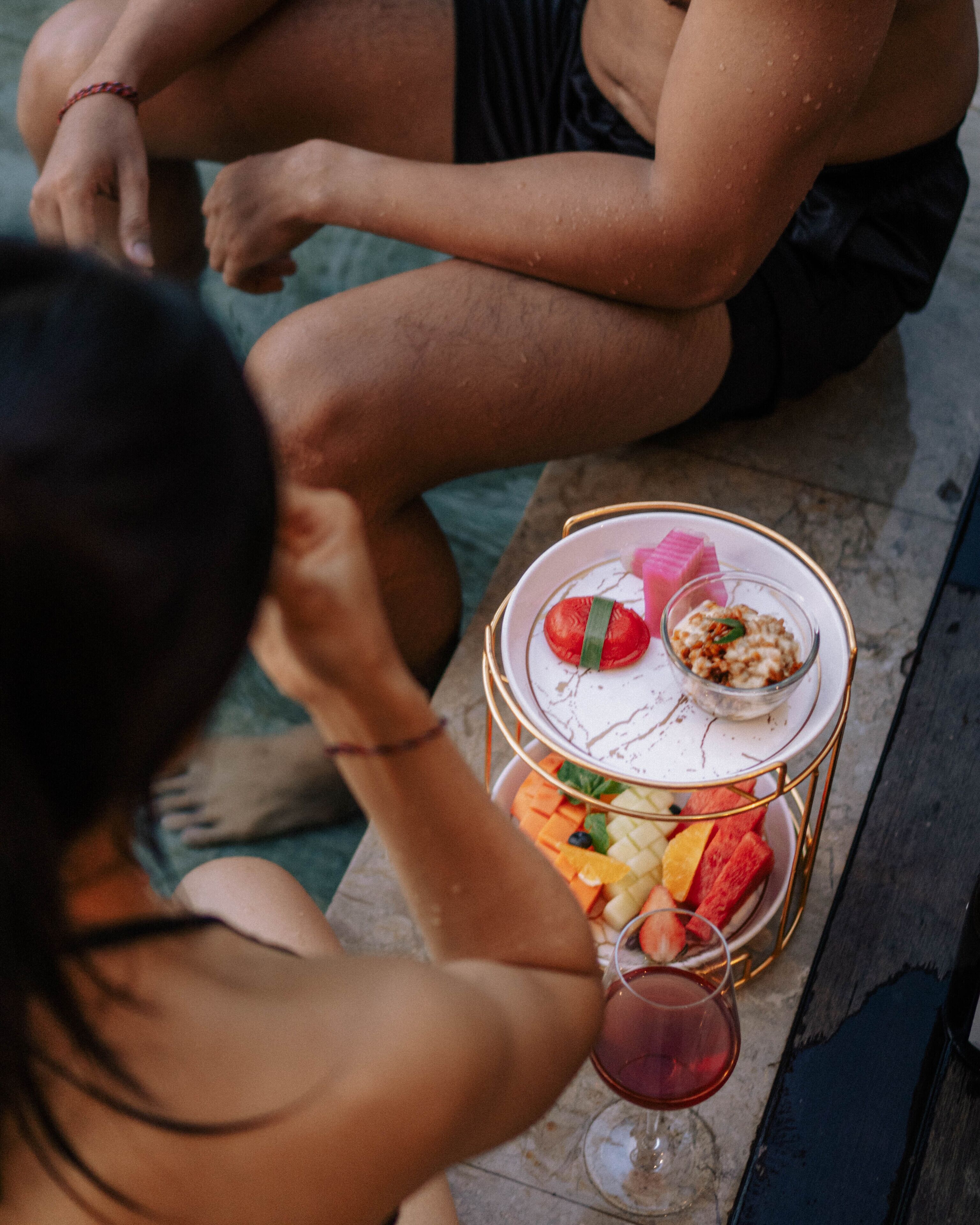 A person sitting on a bench with a tray of food and a drink.