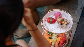 A person sitting on a bench with a tray of food and a drink.