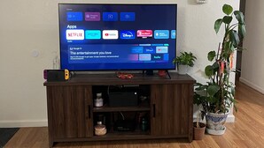 Un téléviseur à écran plat, posé sur un meuble en bois, doté d’une interface numérique affichant diverses applications de diffusion en continu.