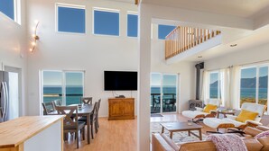 A spacious living area with a large flat-screen TV, wooden dining table, and comfortable seating.