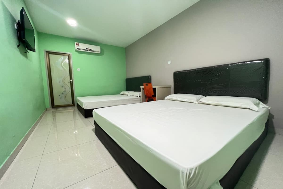 A hotel room with two beds, a television, an air conditioning unit, and a door with a glass panel.