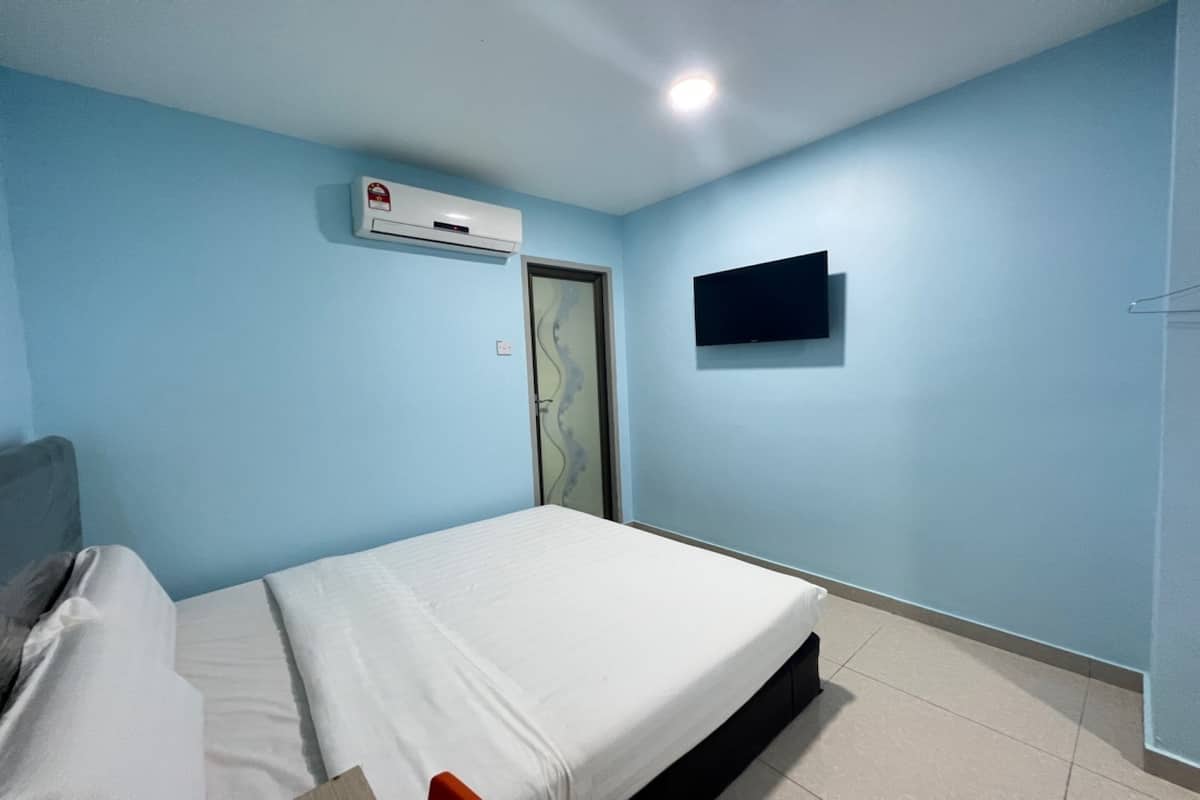 A bedroom with a bed, a wall-mounted TV, and an air conditioning unit.