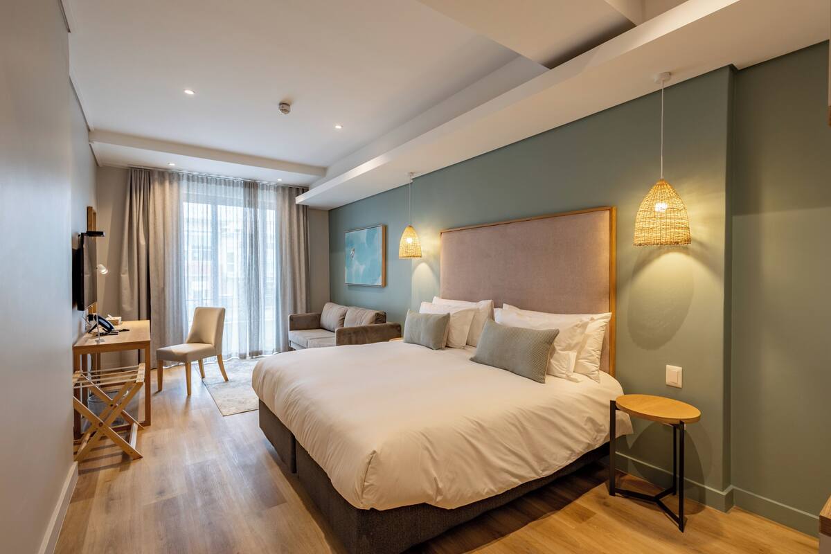 A modern hotel room with a large bed, a desk, and a chair.