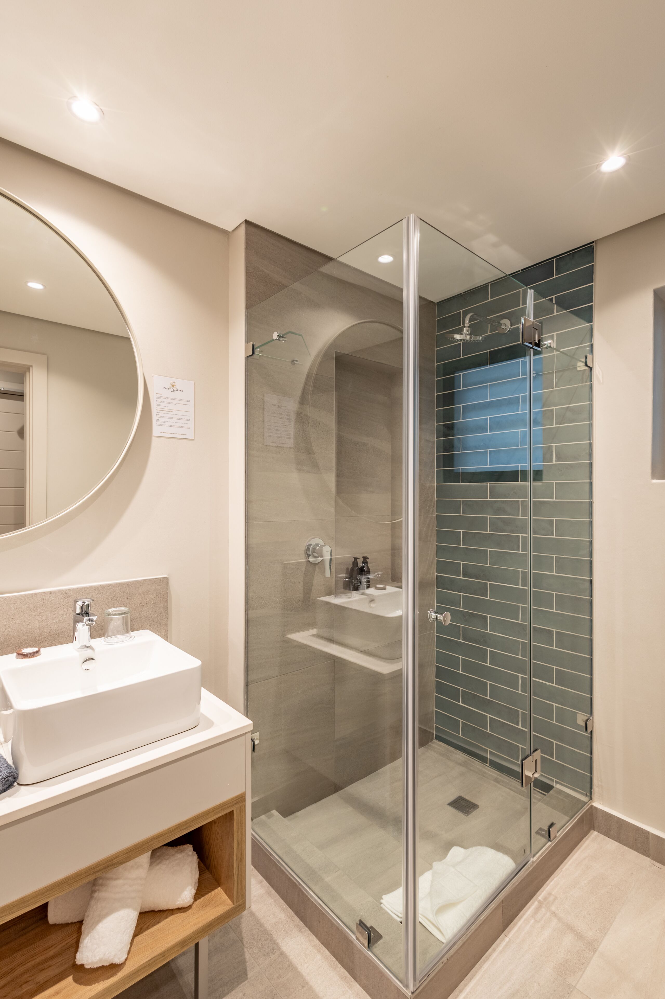 A modern bathroom with a glass-enclosed shower, a white sink, and a mirror.