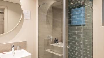 A modern bathroom with a glass-enclosed shower, a white sink, and a mirror.