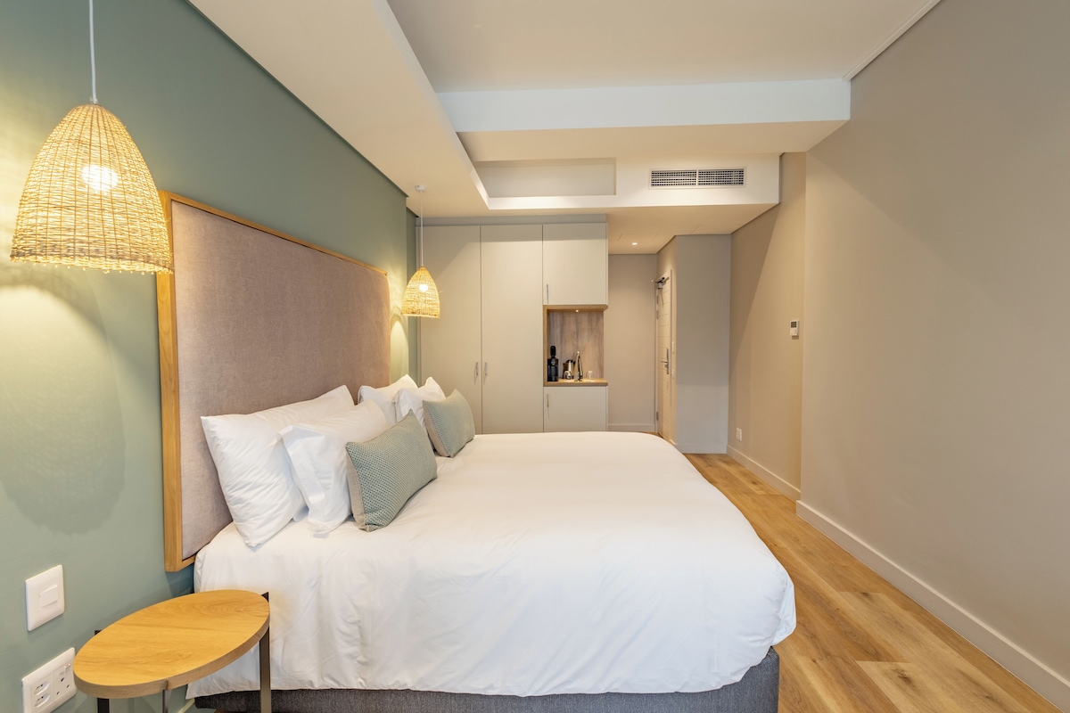 Un dormitorio moderno con una cama grande, mesitas de noche e iluminación colgante.