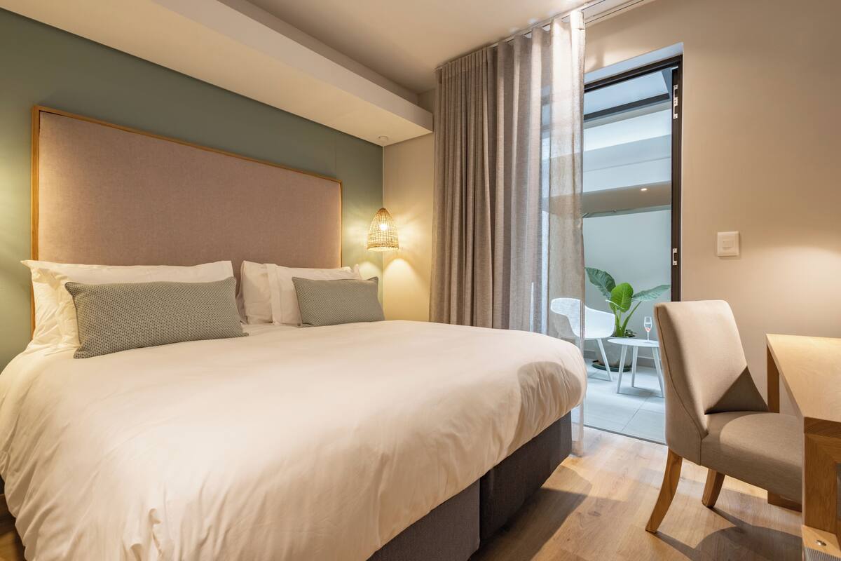 A hotel room with a large bed, a desk, and a chair.