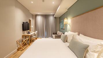 Una habitación de hotel moderna con una cama grande, un escritorio, una silla, un televisor y una ventana con cortinas.