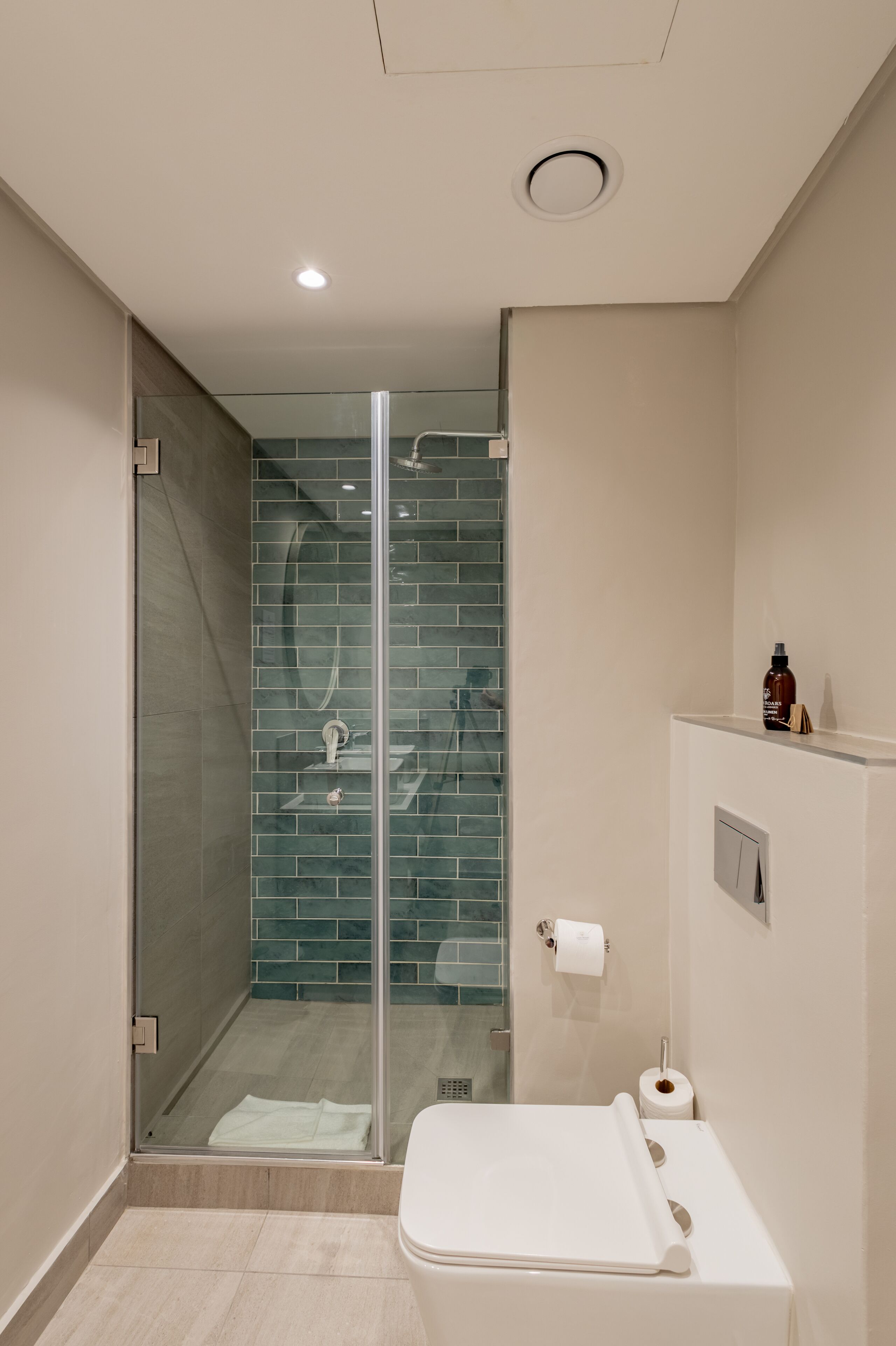 Een moderne badkamer met een glazen douchecabine, een toilet en een wastafel.