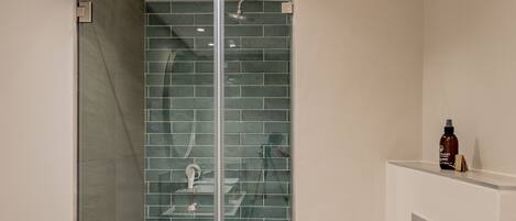 A modern bathroom with a glass-enclosed shower, a toilet, and a sink.